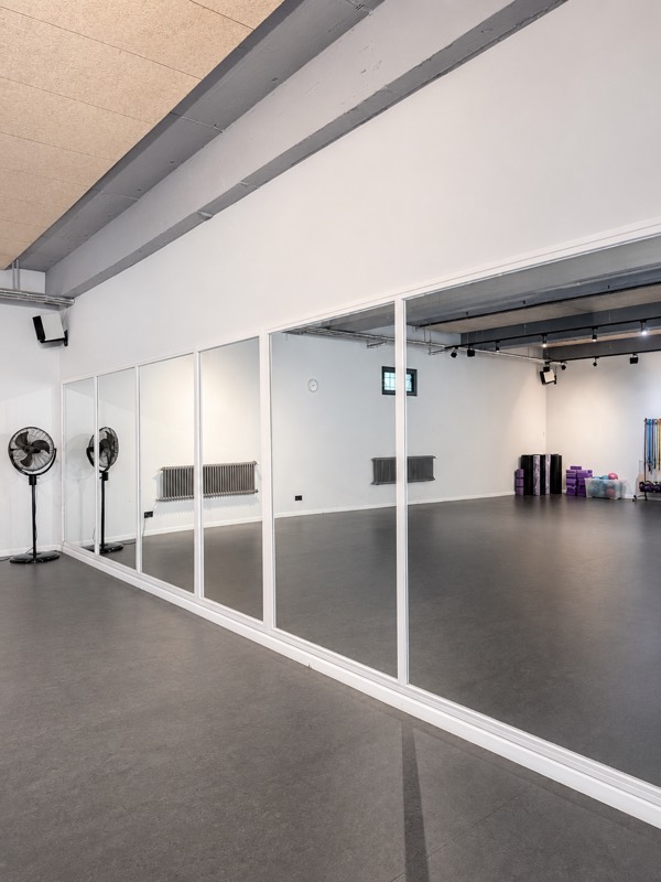 Großer Kursraum mit Spiegelwand für Yoga, HIIT und Gruppenkurse